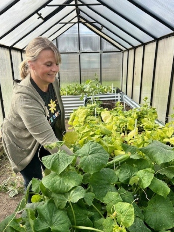 Educator shows plants in a school's greenhouse.